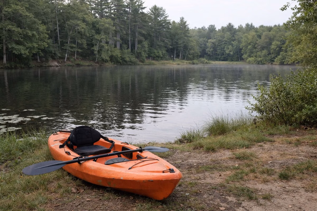 A kayak pulled up on the grassy edge of a small pond